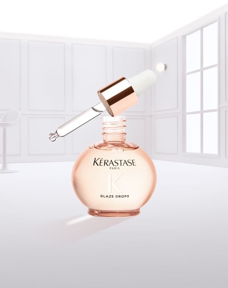 Frasco de suero Glaze Drops de Kerastase, con un liquido rosa goteando.