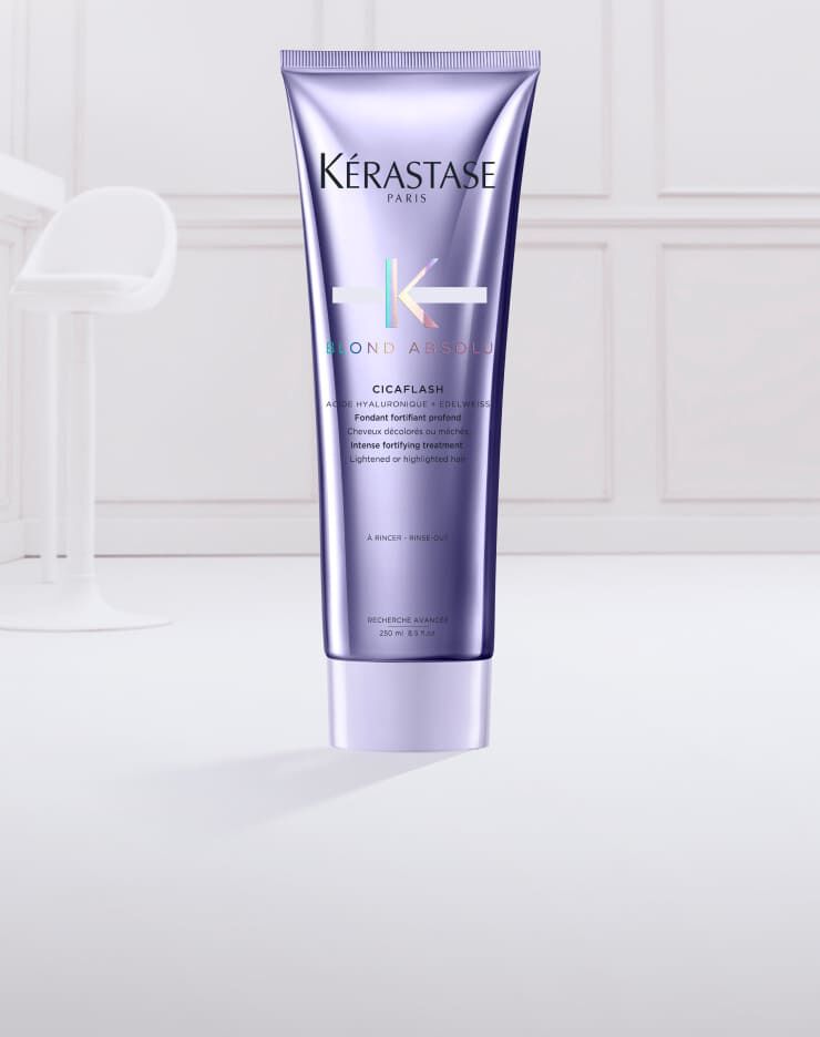 Imagen de un tubo de tratamiento para el cabello de Kerastase, llamado "Cicaflash", con un diseno en tonos morados y un poco de producto en una textura cremosa en la parte inferior.