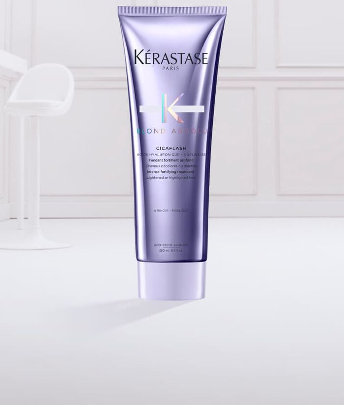 Imagen de un tubo de tratamiento para el cabello de Kerastase, llamado "Cicaflash", con un diseno en tonos morados y un poco de producto en una textura cremosa en la parte inferior.