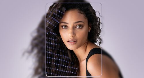 Mujer con cabello rizado y suelto, mirando hacia la camara, con un fondo suave y elegante.
