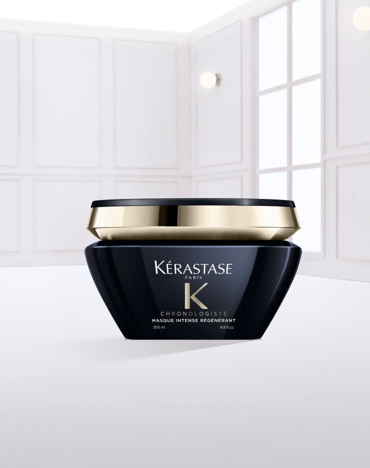 A black jar of Kerastase hair cream with a gold lid, resting on a smooth spread of the cream, set against a light background.