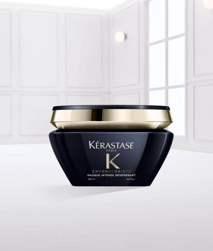 A black jar of Kerastase hair cream with a gold lid, resting on a smooth spread of the cream, set against a light background.
