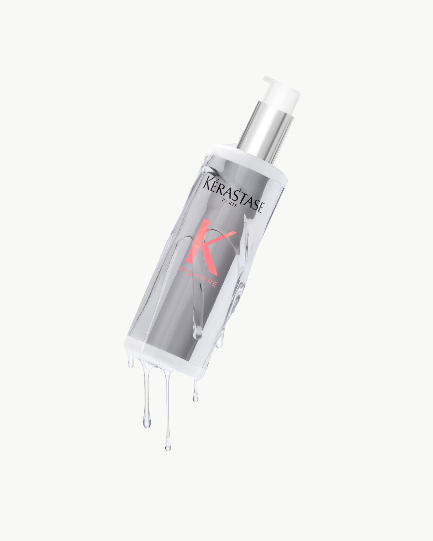 Botella de serum capilar de Kerastase, con liquido goteando y fondo claro.