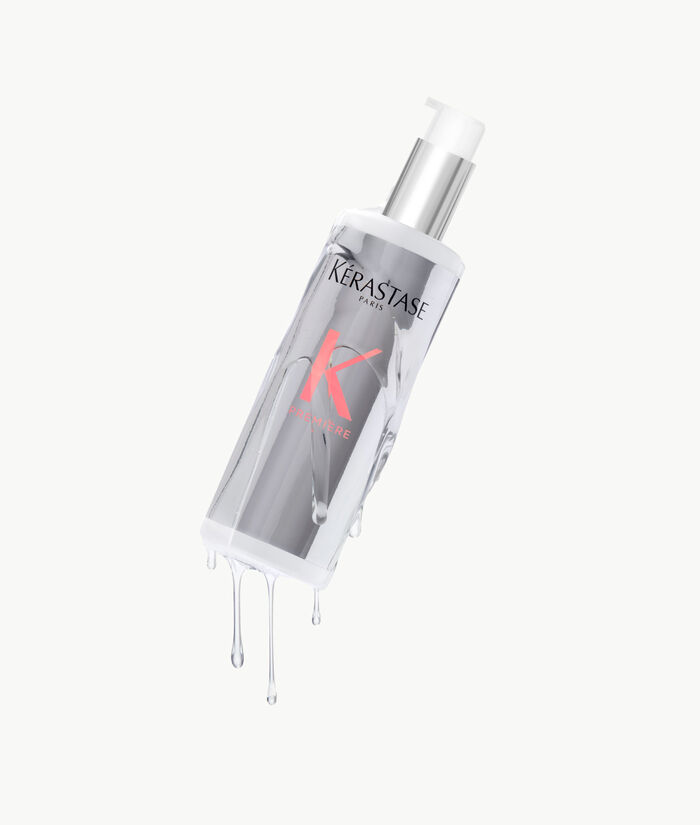 Botella de serum capilar de Kerastase, con liquido goteando y fondo claro.