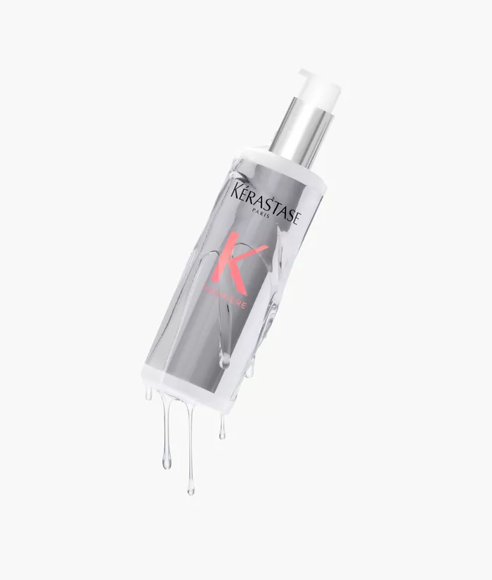 Botella de serum capilar de Kerastase, con liquido goteando y fondo claro.