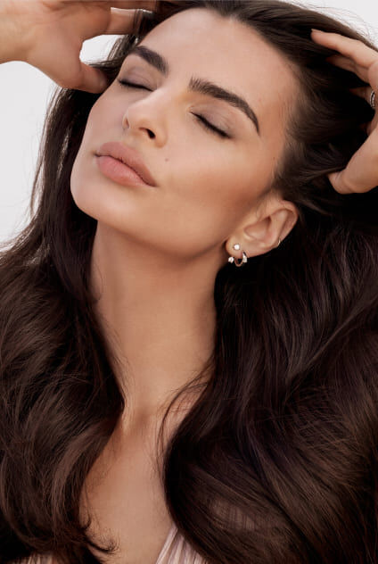 Perfil de una mujer con cabello largo y oscuro sobre un fondo oscuro, enfatizando su silueta y la elegancia de su cabello.