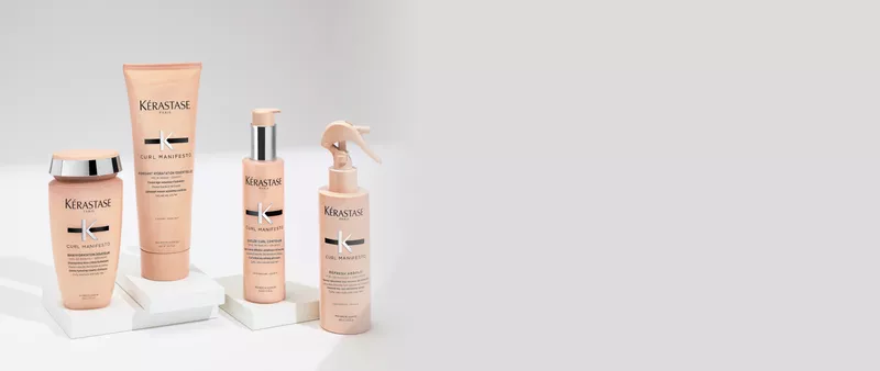 Mano sosteniendo una botella de champu Kerastase Gloss Absolu con un liquido blanco cremoso cayendo sobre ella.