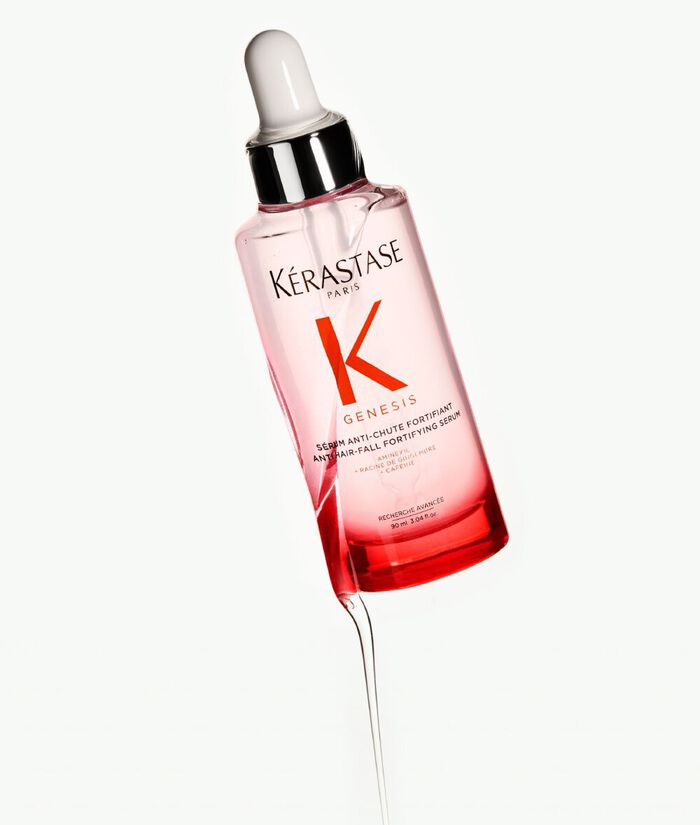 Botella de suero Kerastase Genesis, con un gotero blanco, sobre un fondo claro.