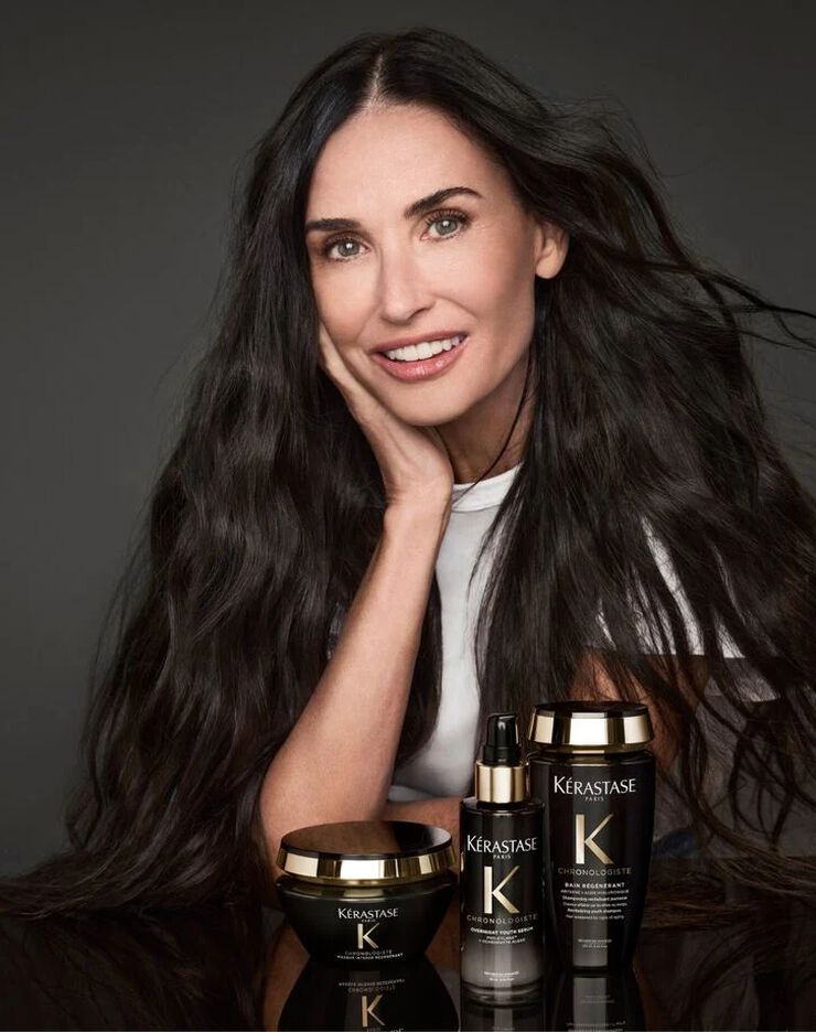 Demi Moore posando con la coleccion de productos capilares Kerastase Chronologiste en envases negros y dorados.