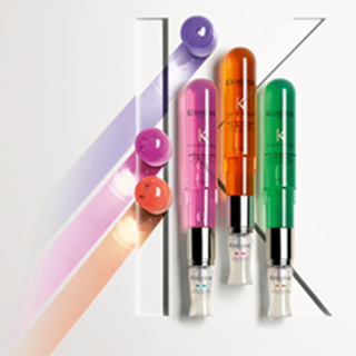 Three colorful skincare serums in bright bottles—pink, orange, and green—are arranged next to graphic, colorful stripes on a white background.