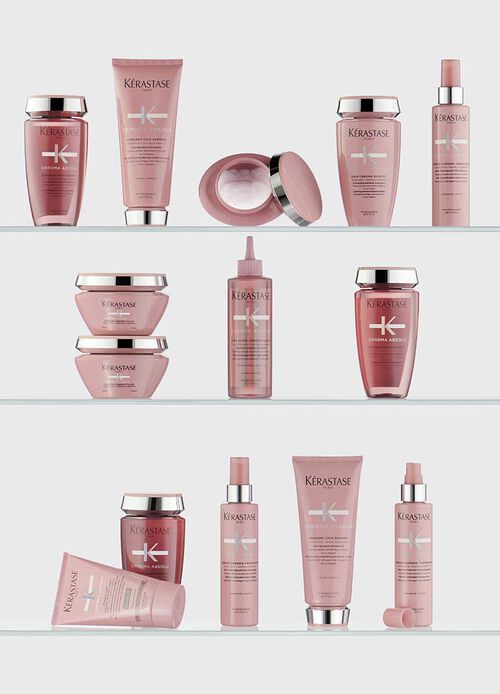 A collection of Kerastase hair care products featuring various bottles and jars, arranged artistically against a vibrant pink background.