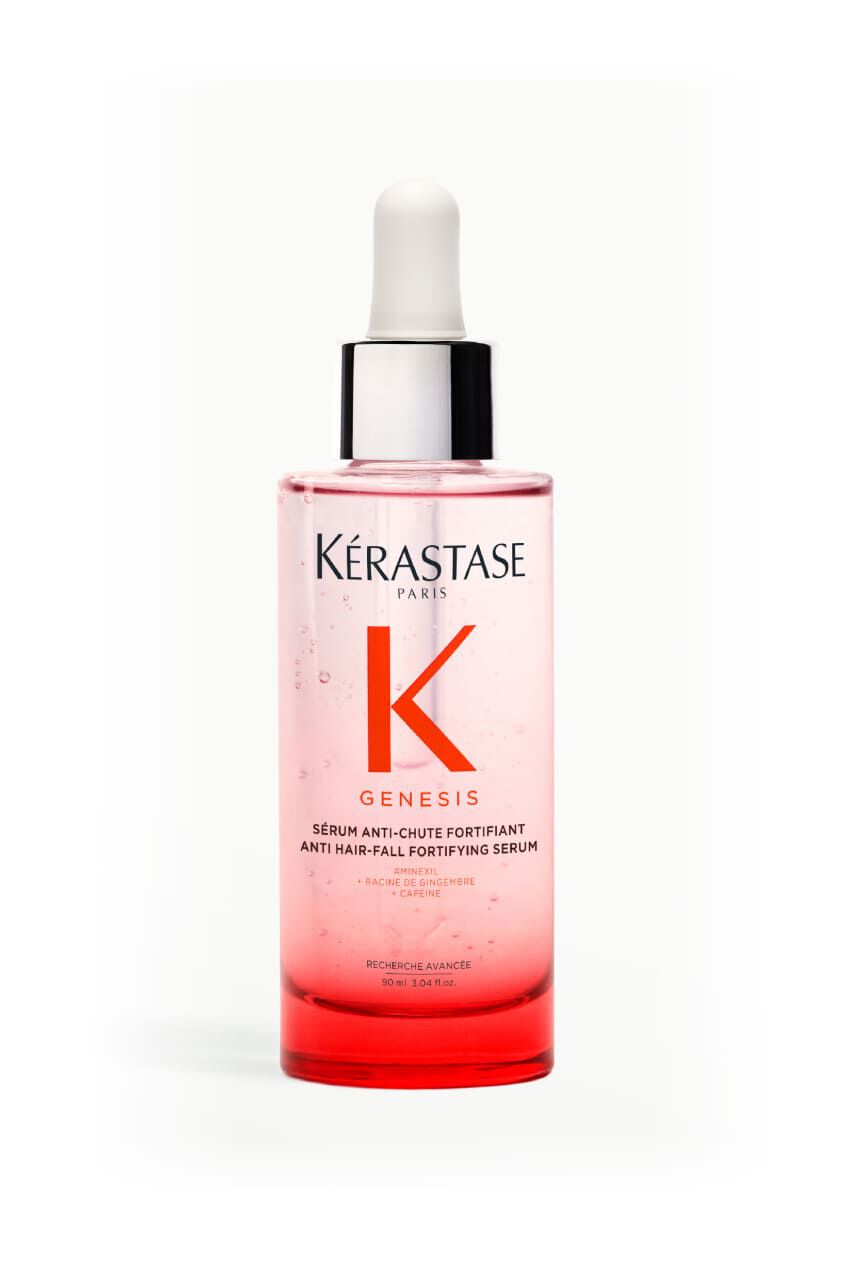 Botella del serum Kerastase Genesis Serum Anti-Chute Fortifiant, rodeada de elementos botanicos como lavanda y jengibre.