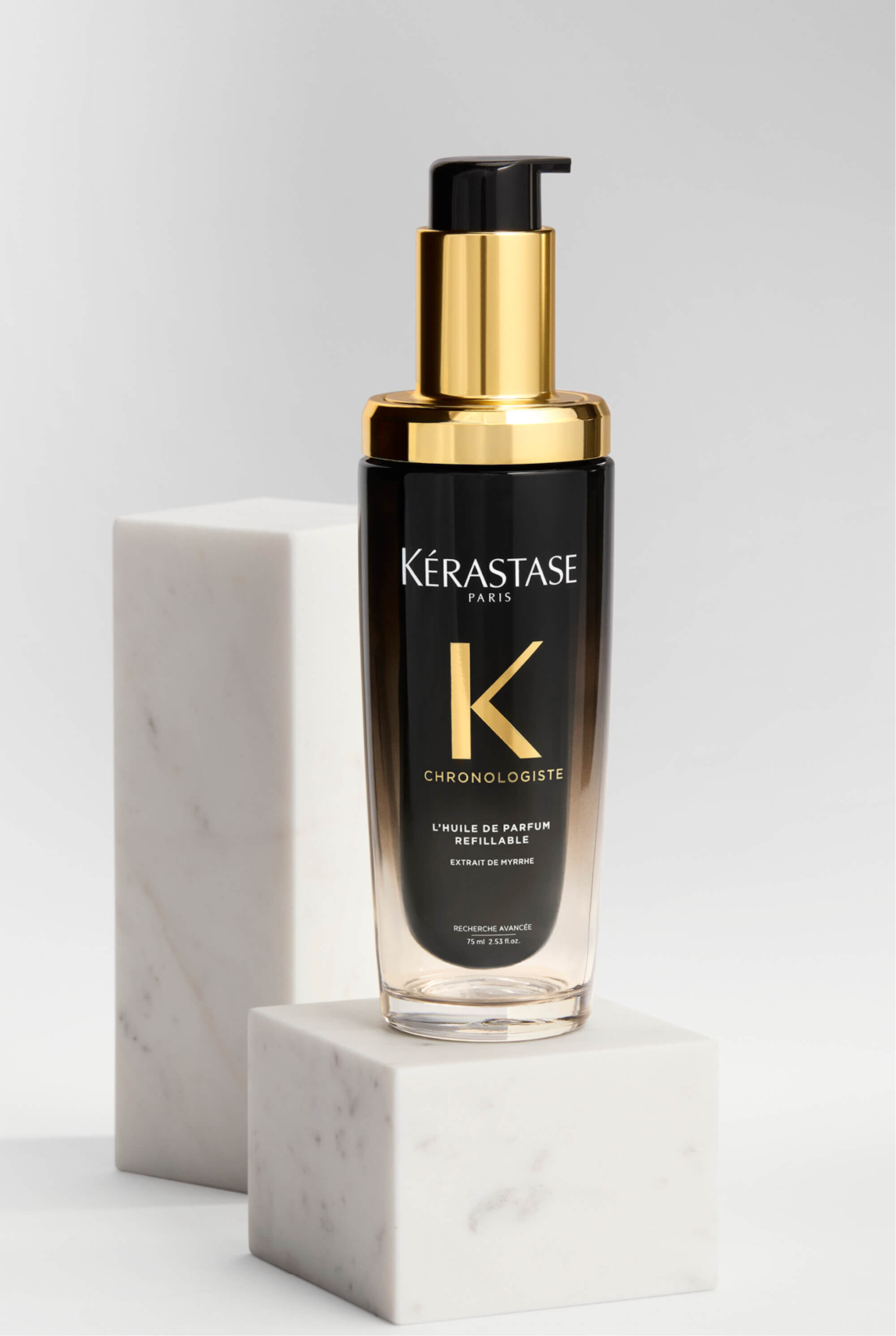 Frasco de Huile de Parfum Chronologiste sobre una plataforma de marmol.​