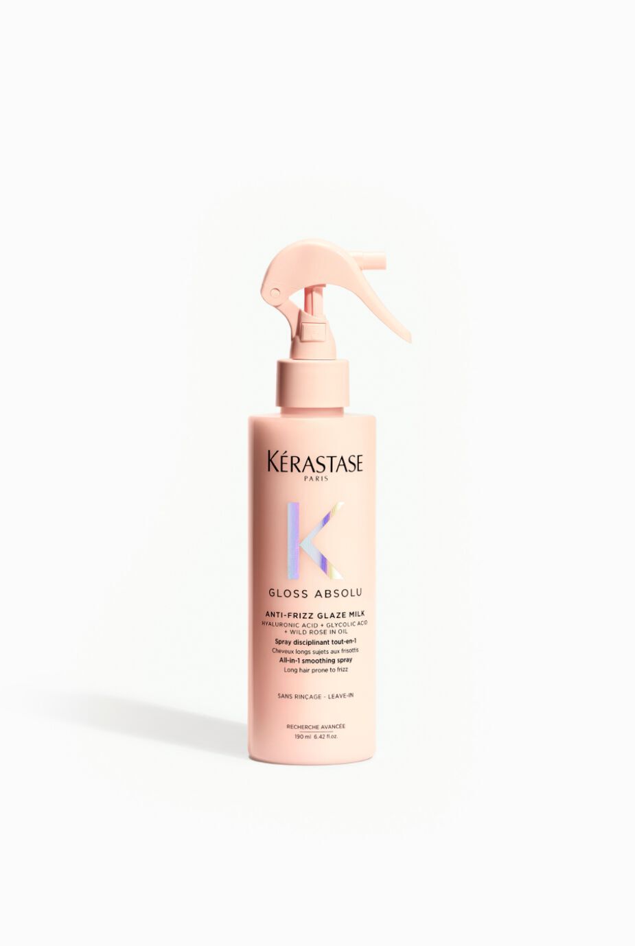 A pink spray bottle of Kerastase Gloss Absolu, labeled as an anti-frizz glaze milk. The bottle features a spray top and is designed for leave-in use.