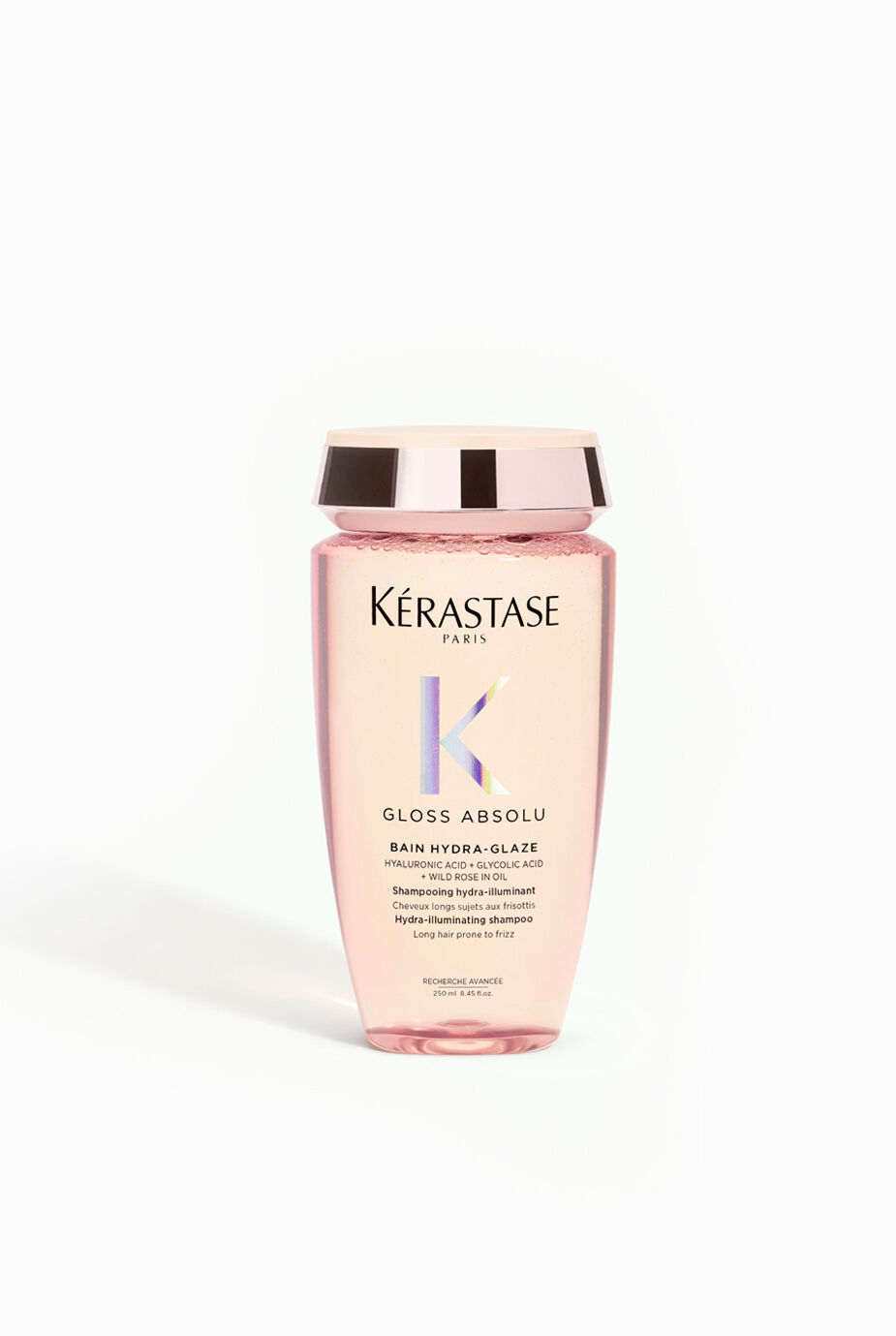 A bottle of Kerastase Gloss Absolu Bain Hydra-Glaze, a pink shampoo designed for hydrating and enhancing shine, with a gold lid and label featuring the brand's logo.