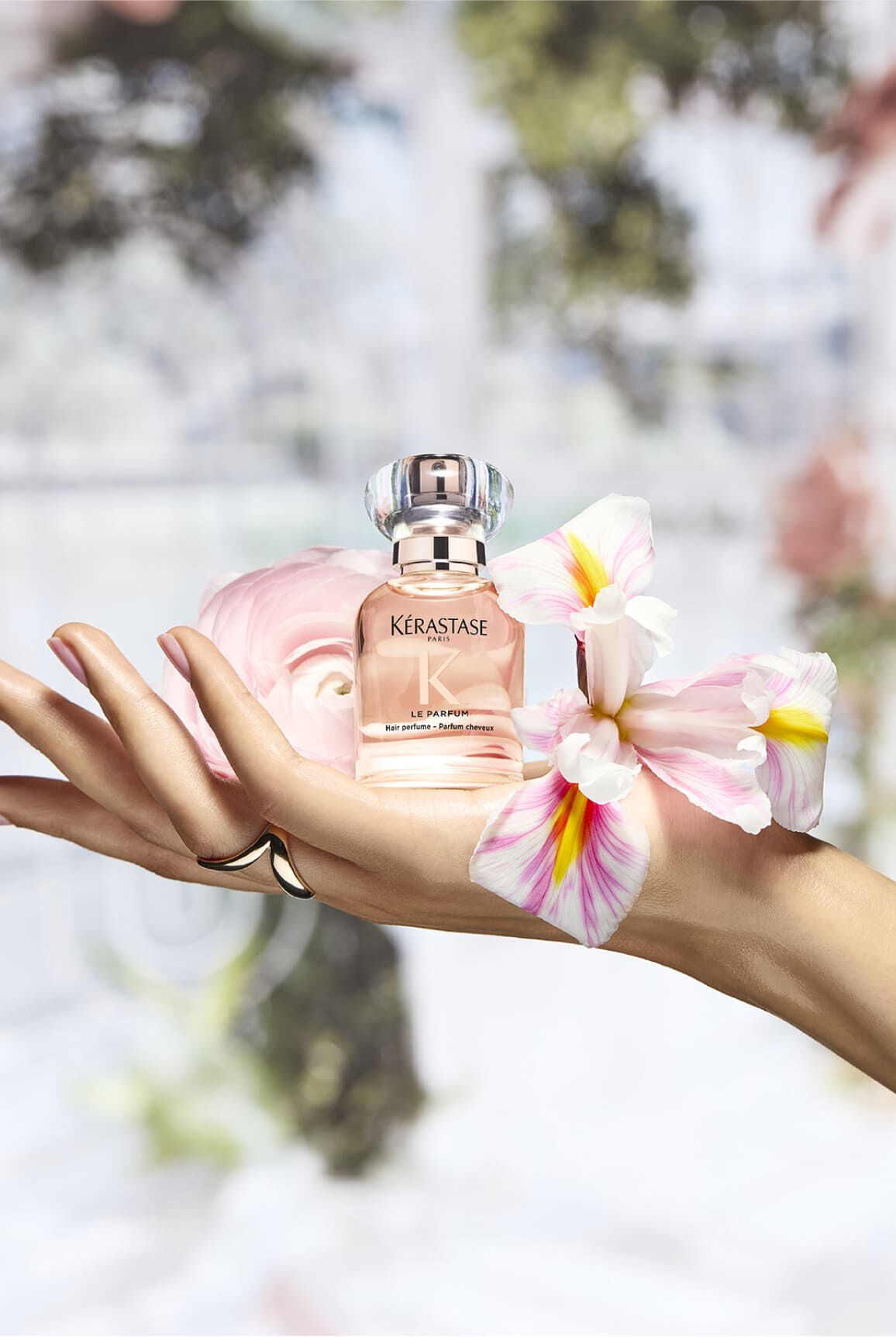 Perfume Gloss Absolu, colocado en una mano en un entorno floral que evoca sus ingredientes