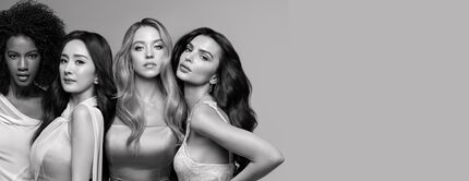 Retrato en blanco y negro de cuatro mujeres con diversos tipos y estilos de cabello posando juntas.