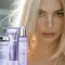A model with long, light blonde hair is featured prominently alongside Kerastase hair care products displayed in the foreground, including shampoo, conditioner, and a treatment. The background has a soft, blurred effect, creating a focus on the model and the products.