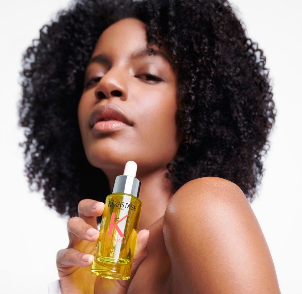 Ebonee Davis, con su magnífica melena rizada, luce el mejor aceite para cabello dañado Première Huile Gloss Réparatrice.
